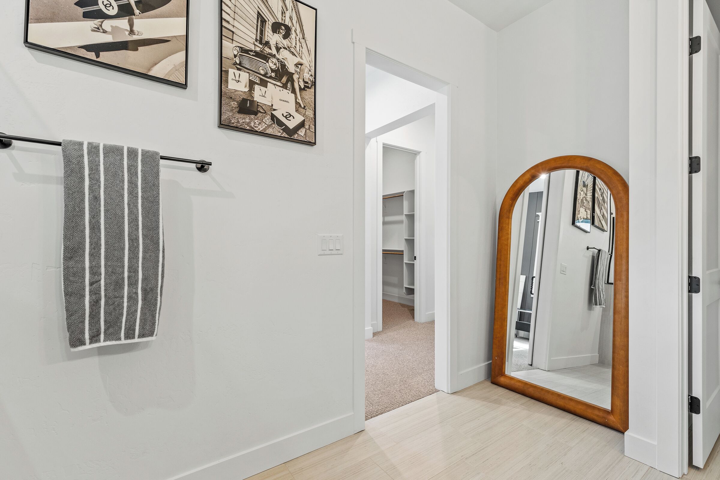A hallway with a striped towel, a framed picture, and a mirror with a wooden frame.