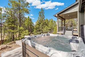 A hot tub with a wooden deck and a covered seating area, surrounded by trees. - Valerian Flagstaff (Flagstaff)