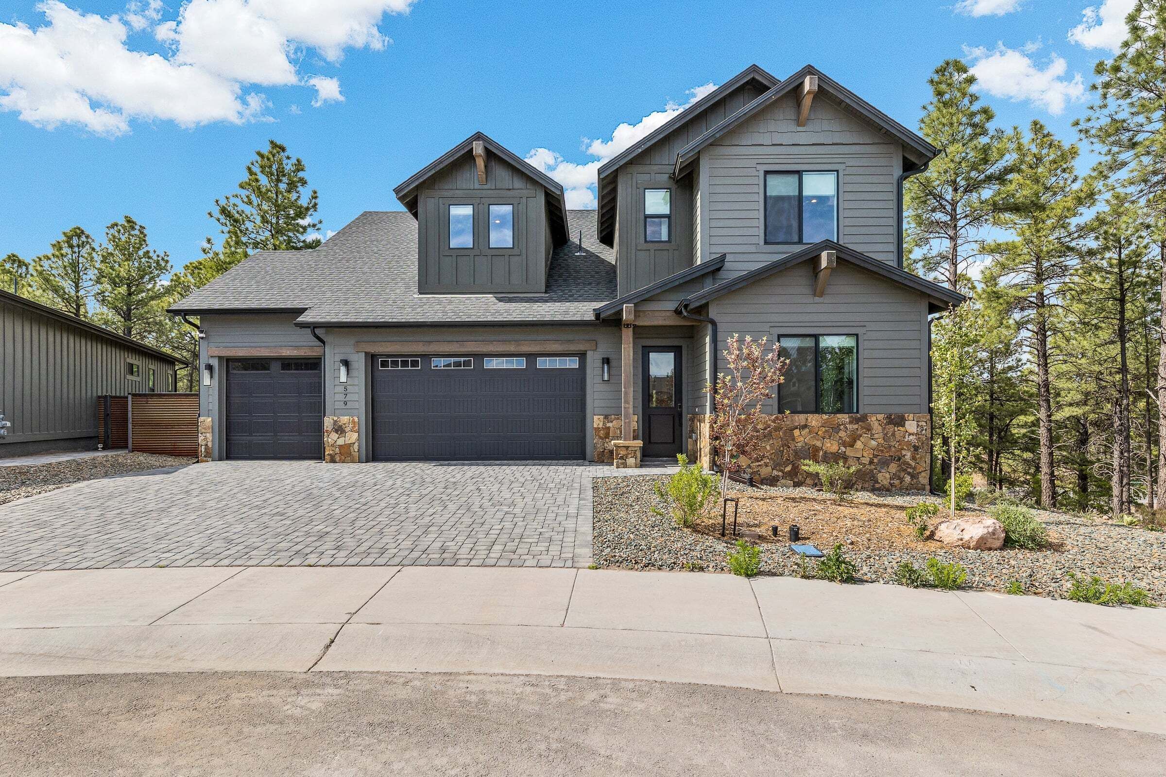 A two-story house with a garage, a stone accent wall, and a landscaped driveway.