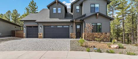 A two-story house with a garage, a stone accent wall, and a landscaped driveway.