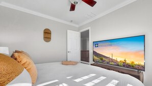 A bedroom with a bed, a ceiling fan, a TV, and a door leading to another room. - Magic of Maricopa (Maricopa)