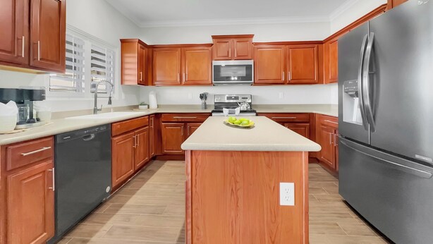 A modern kitchen with wooden cabinets, stainless steel appliances, and a central island. - Magic of Maricopa (Maricopa)