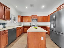 A modern kitchen with wooden cabinets, stainless steel appliances, and a central island.