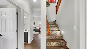 A hallway with a white door, a staircase with patterned steps, and a living area in the background. - Magic of Maricopa (Maricopa)