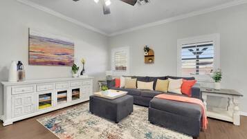 A living room with a ceiling fan, a sofa set, a white cabinet, and a colorful rug.