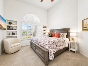 A bedroom with a bed, a chair, a nightstand, a lamp, and a window with blinds. - Trailridge Mesa (Mesa)