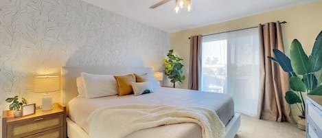 A bedroom with a bed, bedside table, lamp, and a ceiling fan.