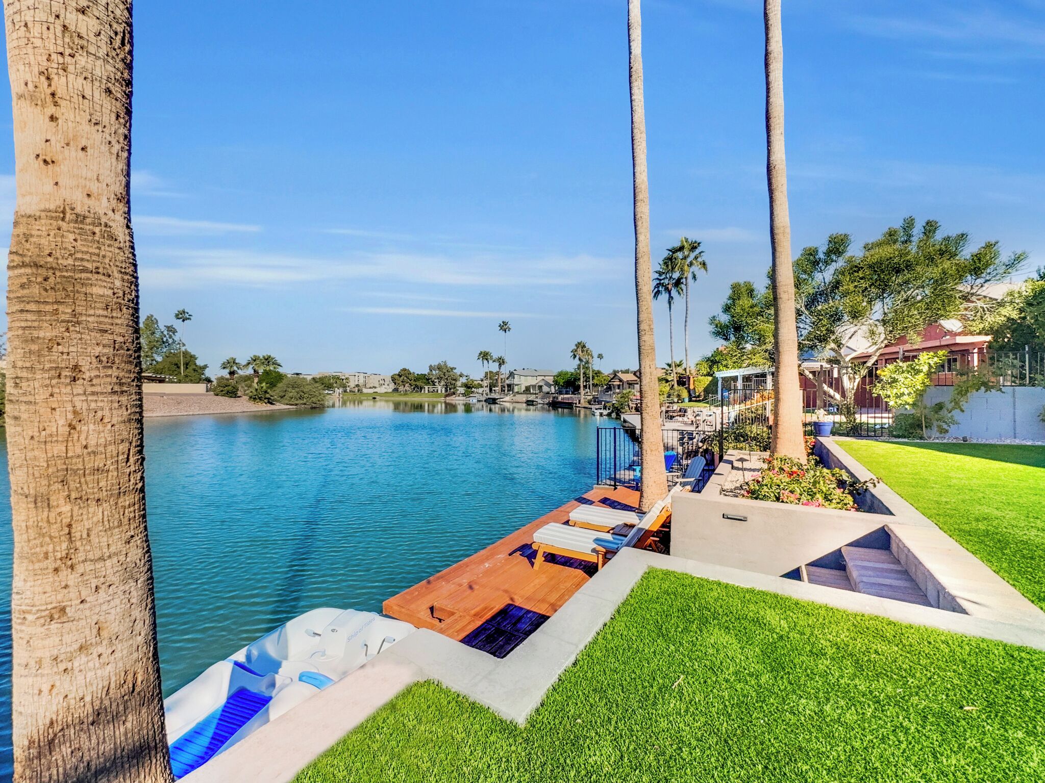 Un espace aménagé au bord de la piscine, offrant une vue dégagée sur l’eau, avec des chaises longues et une pelouse bien entretenue.