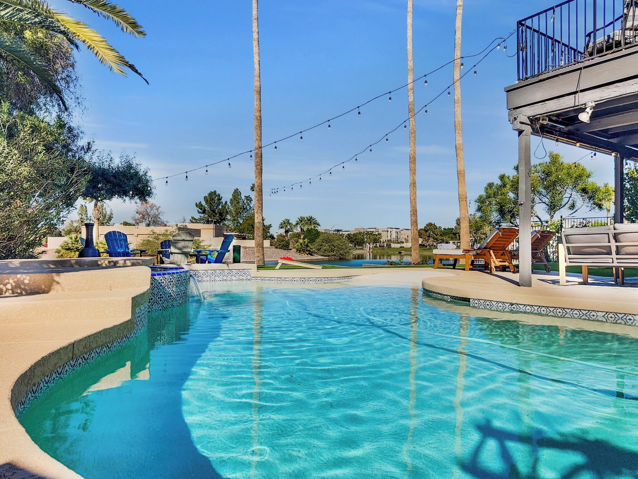 A clear swimming pool with lounge chairs and a pergola.
