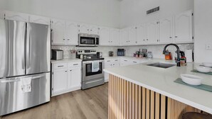 A modern kitchen with white cabinetry, stainless steel appliances, and a central island. - Delta Mesa (Mesa)