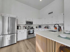 A modern kitchen with white cabinetry, stainless steel appliances, and a central island. - Delta Mesa (Mesa)