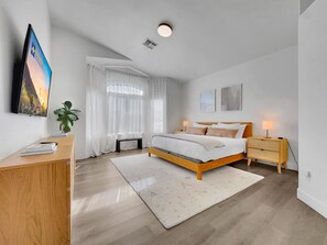 A modern bedroom with a bed, bedside tables, a desk, and a TV. - Delta Mesa (Mesa)