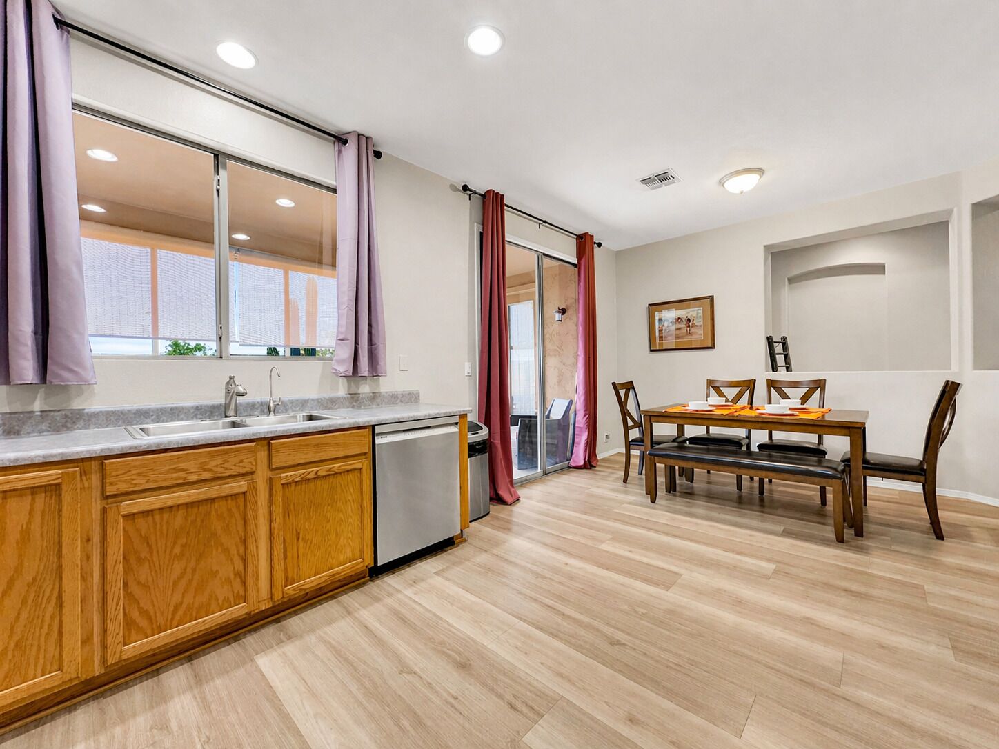 A modern kitchen with wooden cabinets, a sink, and a dining area with a table and chairs.