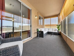 A modern interior with a glass sliding door, a sofa, a small table, and a potted plant. - Hacienda La Noria Gold Canyon (Gold Canyon)