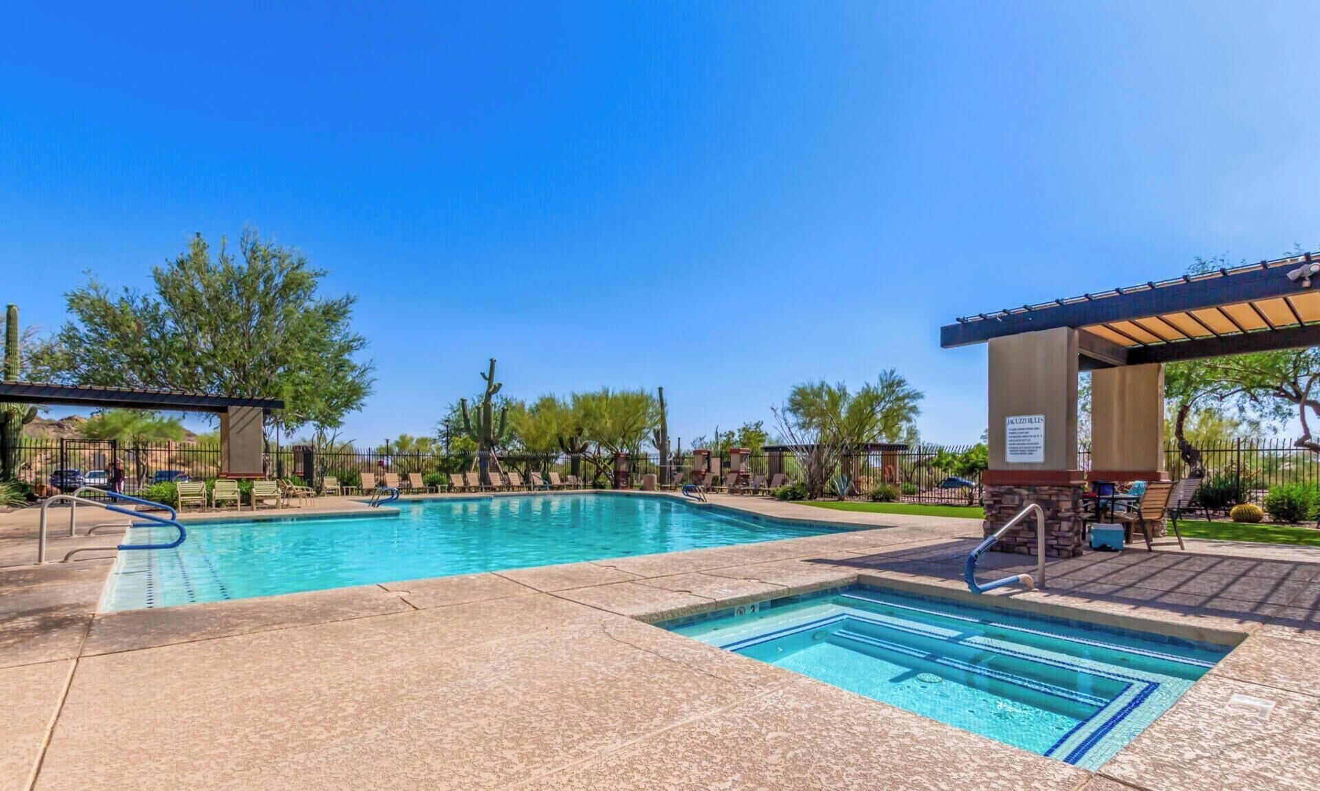 A pool area with clear blue water, lounge chairs, and a covered seating area.