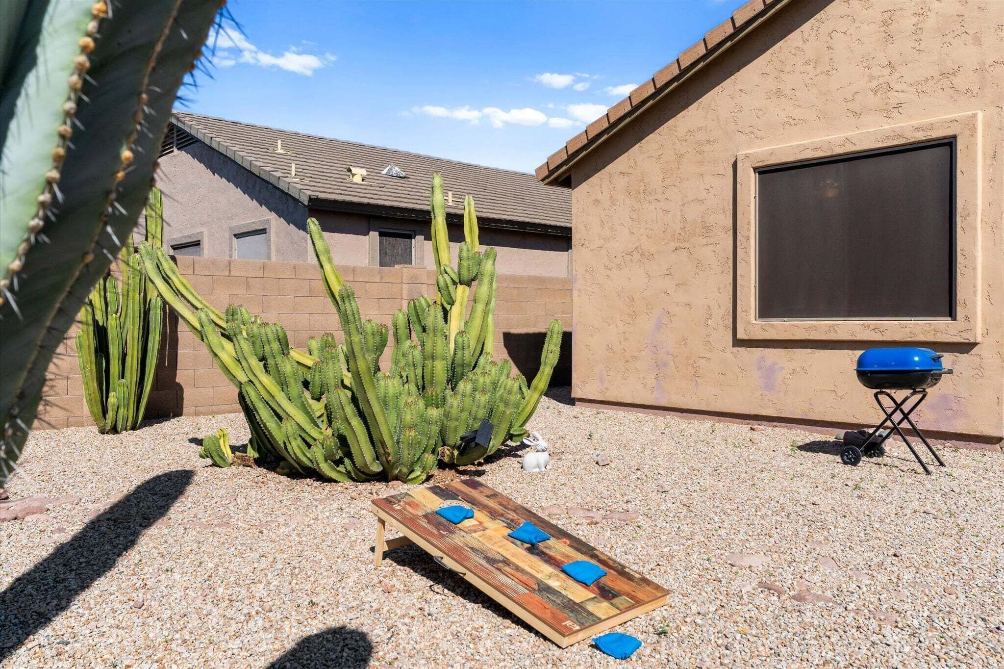 A patio with a wooden board game, a barbecue grill, and cacti.
