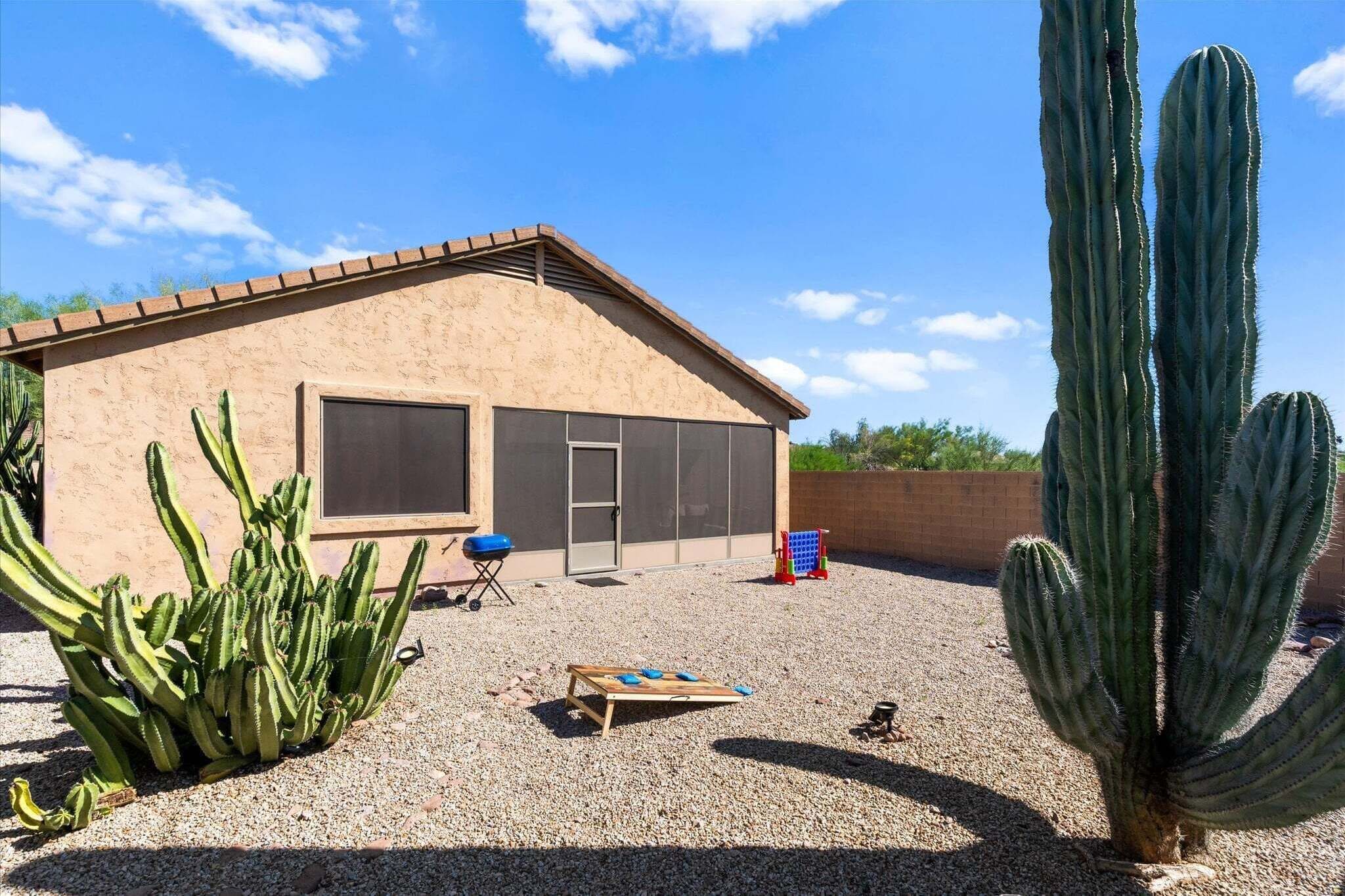Una casa con un patio, un cactus grande y una parrilla.