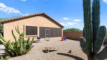 Una casa con un patio, un cactus grande y una parrilla.