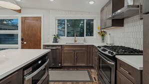 Une cuisine moderne dotée d’appareils électroménagers en acier inoxydable, d’une grande fenêtre et offrant une vue sur l’extérieur.