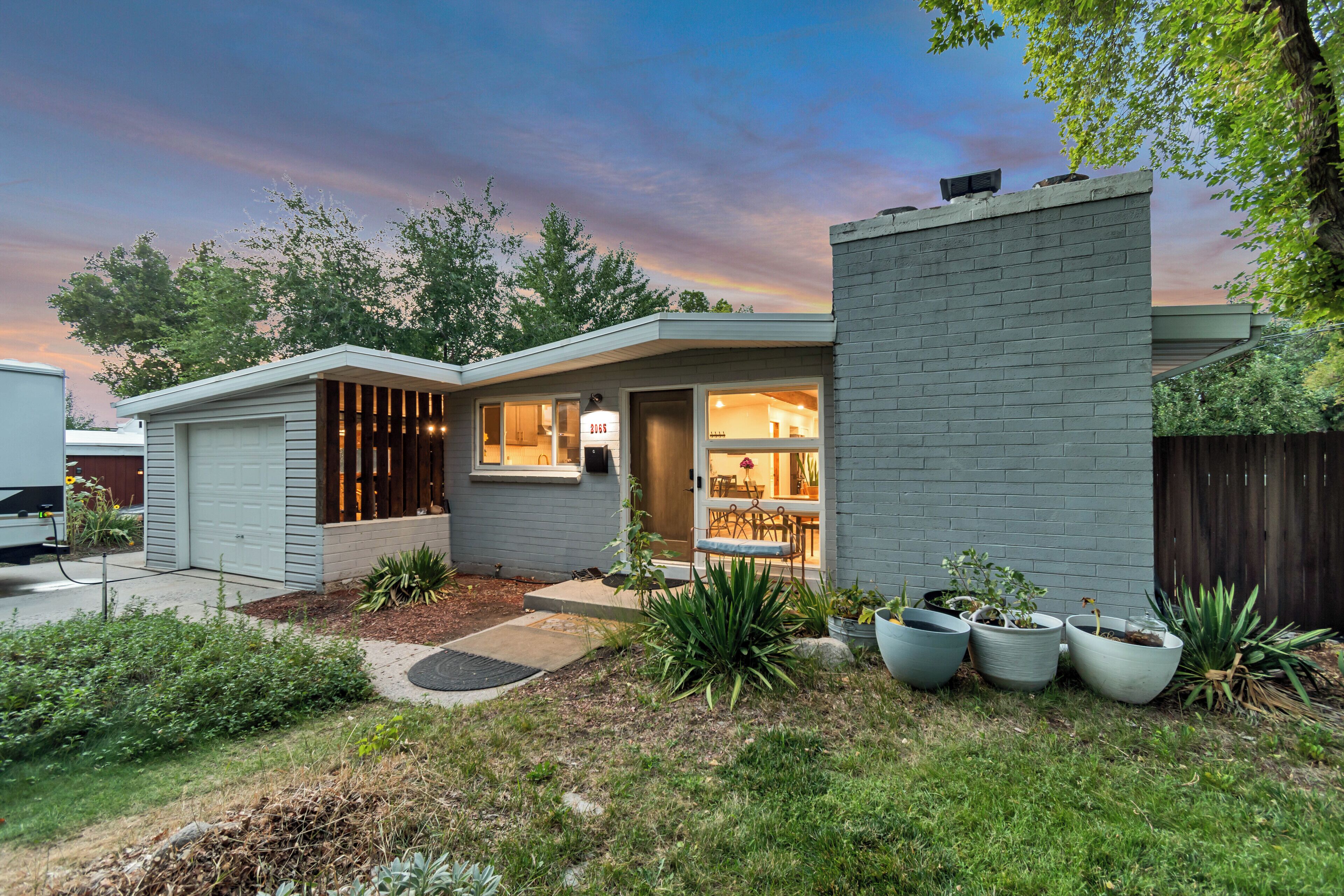 A modern house with a garage, a covered porch, and a well-maintained garden.