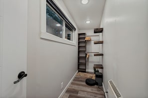 Ein schmaler Flur mit Fenster, Holzdielen und integrierten Regalelementen.