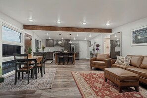 A modern kitchen with a central island, wooden dining table, and chairs. - Relaxing Mid-Century Home Near Ski Resorts with SwimSpa & EV Charger (Cottonwood Heights)