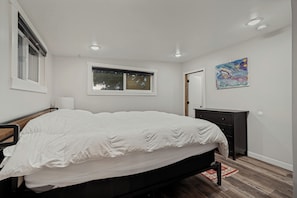 Un dormitorio con cama, c ómoda, ventana y un cuadro en la pared.