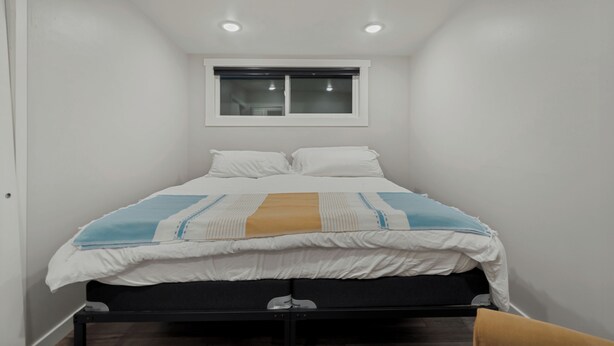 Une chambre à coucher avec un lit, une fenêtre et un luminaire au plafond.