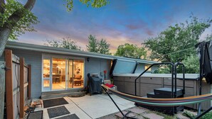 Un jardin avec une terrasse couverte, un hamac et une plateforme en bois.