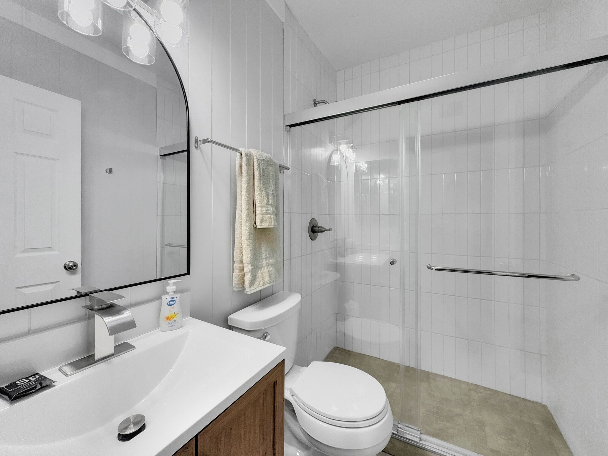 A bathroom with a white sink, toilet, and shower.