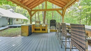 An outdoor deck with a wooden pergola, a grill, and wicker chairs. - Fish and Swim: Home w/ Catskill Creek Views! (East Durham)