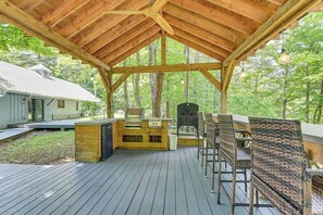 An outdoor deck with a wooden pergola, a grill, and wicker chairs. - Fish and Swim: Home w/ Catskill Creek Views! (East Durham)