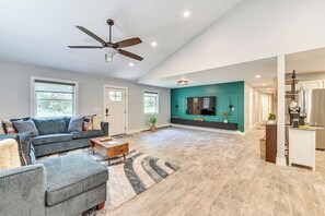 A spacious living room with a large sofa, a coffee table, and a ceiling fan. - Fish and Swim: Home w/ Catskill Creek Views! (East Durham)