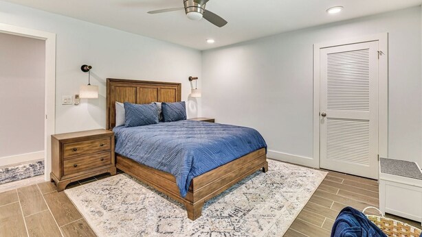 A bedroom with a bed, nightstands, a ceiling fan, a wall-mounted lamp, and a door. - Fish and Swim: Home w/ Catskill Creek Views! (East Durham)