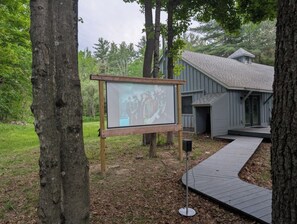 A wooden signboard with a projection screen, a grey building with a sloped roof, and a wooden walkway. - Fish and Swim: Home w/ Catskill Creek Views! (East Durham)
