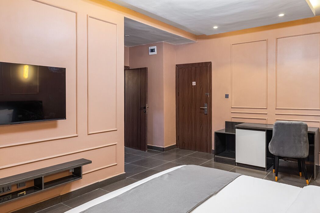 Una habitación de hotel con cama, televisor, escritorio y silla.