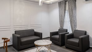 Una sala de estar moderna con un sofá, dos sillones, una mesita de centro y una silla de madera.