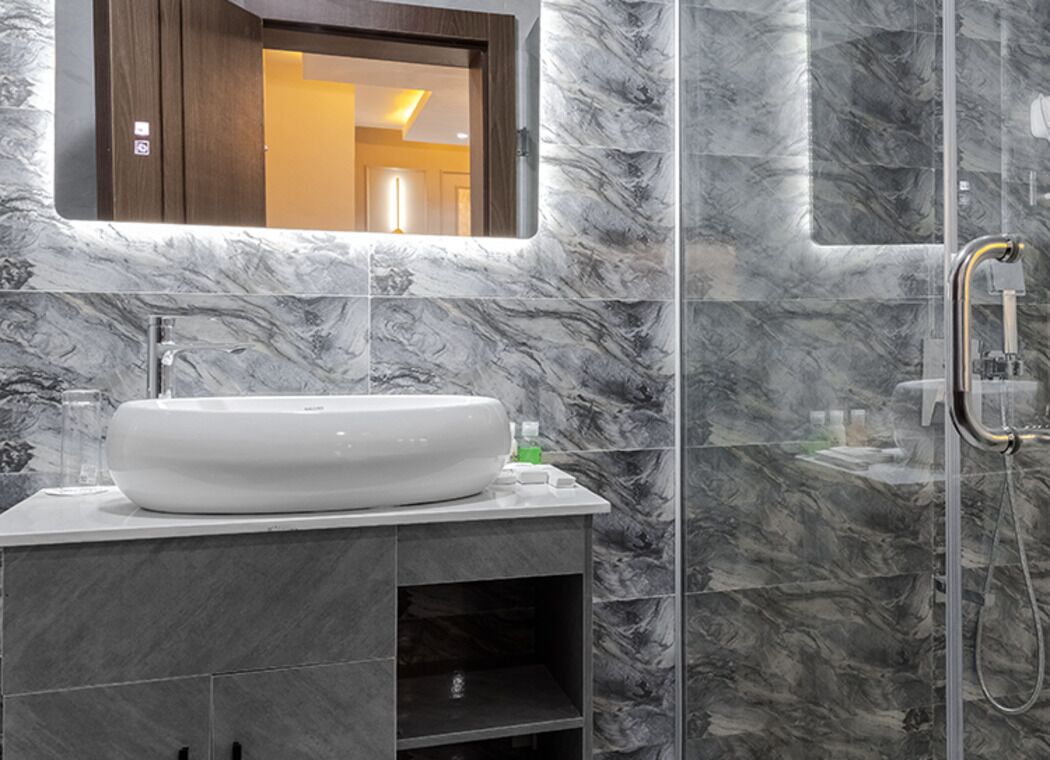 Ein Badezimmer mit Marmorwaschbecken, einem Spiegel und einer Dusche.