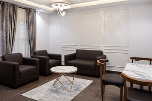 A modern living room with a sofa set, a round coffee table, and a dining table with chairs.