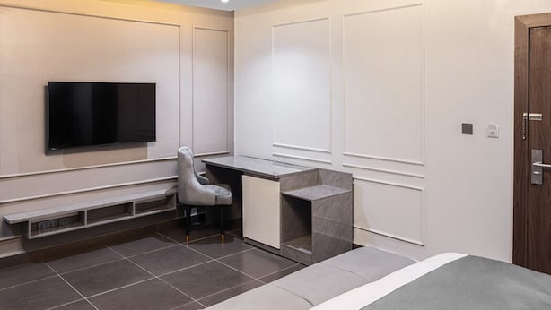 Un dormitorio moderno con cama, escritorio, silla y televisión.