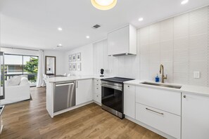 Eine moderne Küche mit weißen Schränken, einem Edelstahlbackofen und einem großen Fenster.