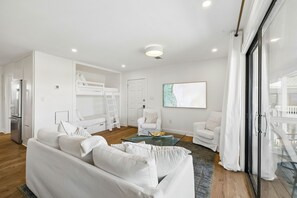 Ein modernes Wohnzimmer mit einem weißen Sofa, einem Glastisch und einem weißen Sessel.