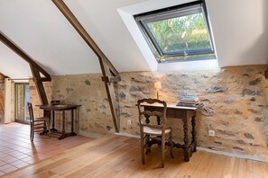 A room with a sloped ceiling, a skylight, a wooden table, a chair, and a stone wall. - Holiday Home 'Folperdrix' with Private Terrace and Garden (Surzur)