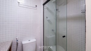 A bathroom with white tiled walls, a glass shower enclosure, a toilet, and a towel rack. - Studio in Cond. With Pool and gym Soa0906 (Salvador)