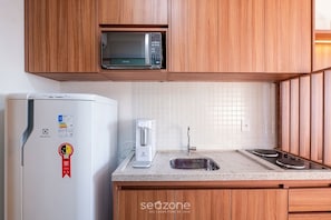 Eine Küche mit Holzausstattung, einem weißen Kühlschrank, einer Mikrowelle, einer Kaffeemaschine und einem Spülbecken.