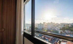 Blick aus einem Fenster mit Stadtlandschaft im Hintergrund, einschließlich Gebäude und blauem Himmel.