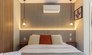 A modern hotel room with a large bed, a wall-mounted air conditioner, and two bedside tables. - Studio With Balcony in a Cond. With gym Hmj0714 (São Paulo)