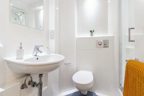 A bathroom with a white sink, a toilet, and a shower area. - Student Only Print Hall (Underpass)