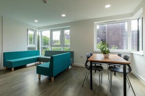 Ein modernes Zimmer mit einer Eckcouch, einem Esstisch mit Stühlen und großen Fenstern mit Blick auf die Stadt.