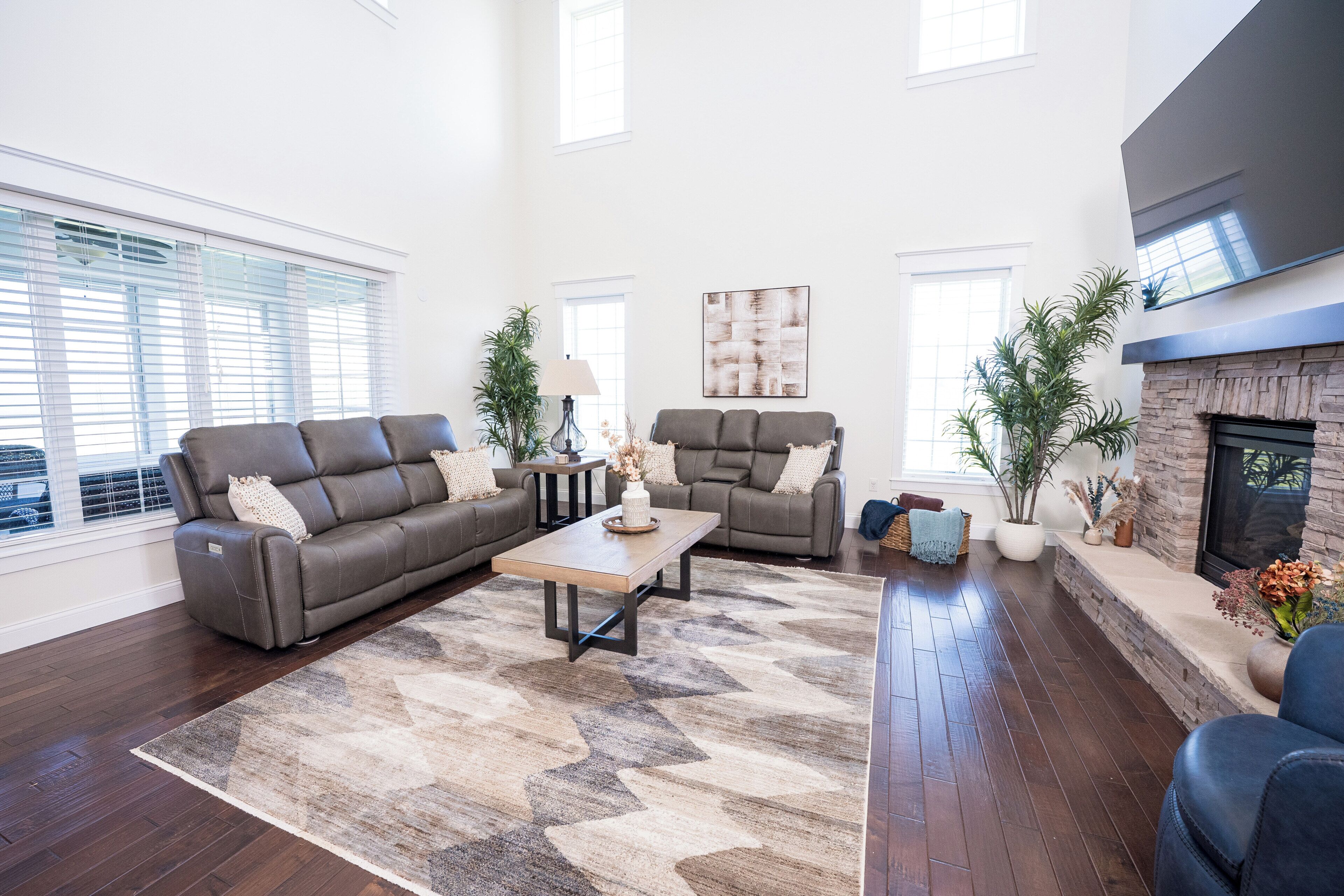 A spacious living room with a fireplace, two sofas, a coffee table, and a large window with blinds.